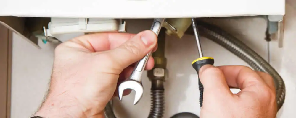 Boiler repair technician tightening pipe fittings and connections in Tulsa, OK