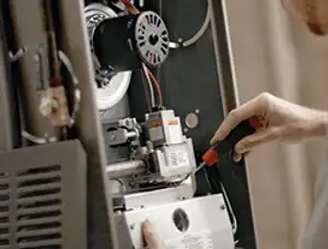 Furnace repair technician inspecting internal components and wiring in Tulsa, OK