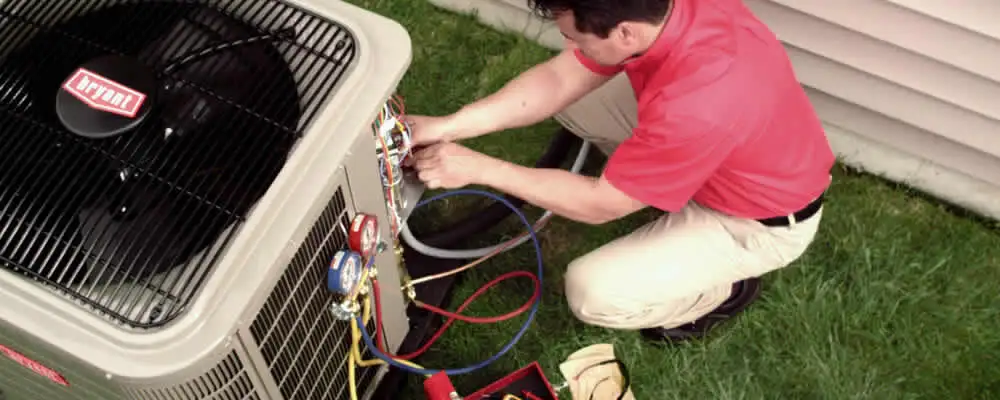 HVAC technician servicing an outdoor air conditioner unit in Tulsa, OK
