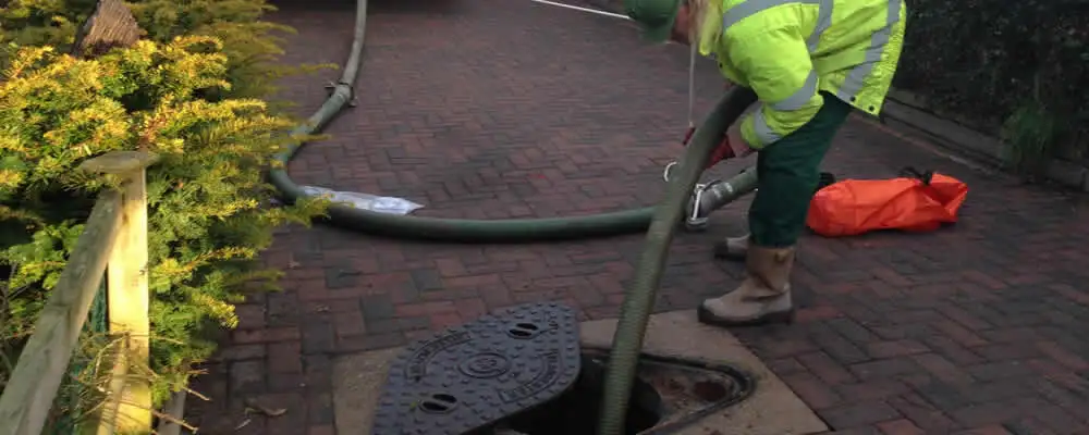 Septic tank cleaning technician servicing a septic tank with a vacuum hose in Tulsa, OK