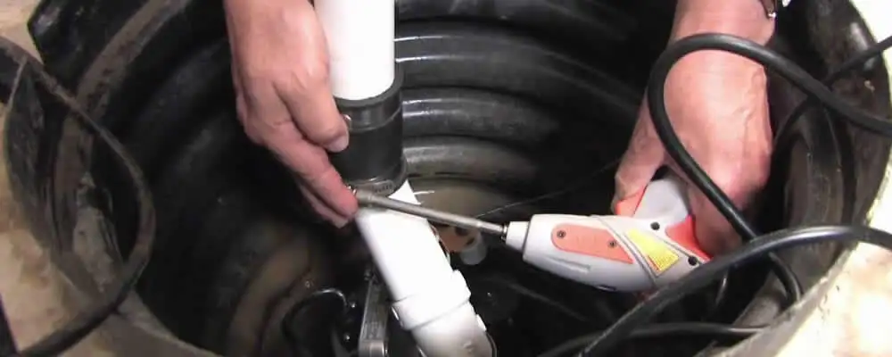 Sump pump installation technician connecting PVC discharge piping in Tulsa, OK