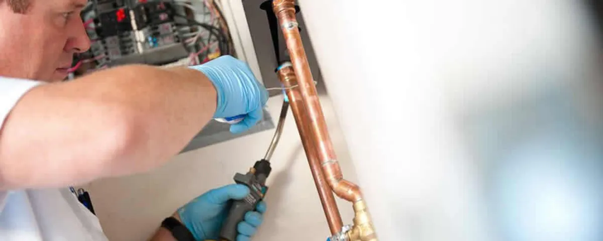 Water heater repair technician testing copper pipe connections and controls in Tulsa, OK